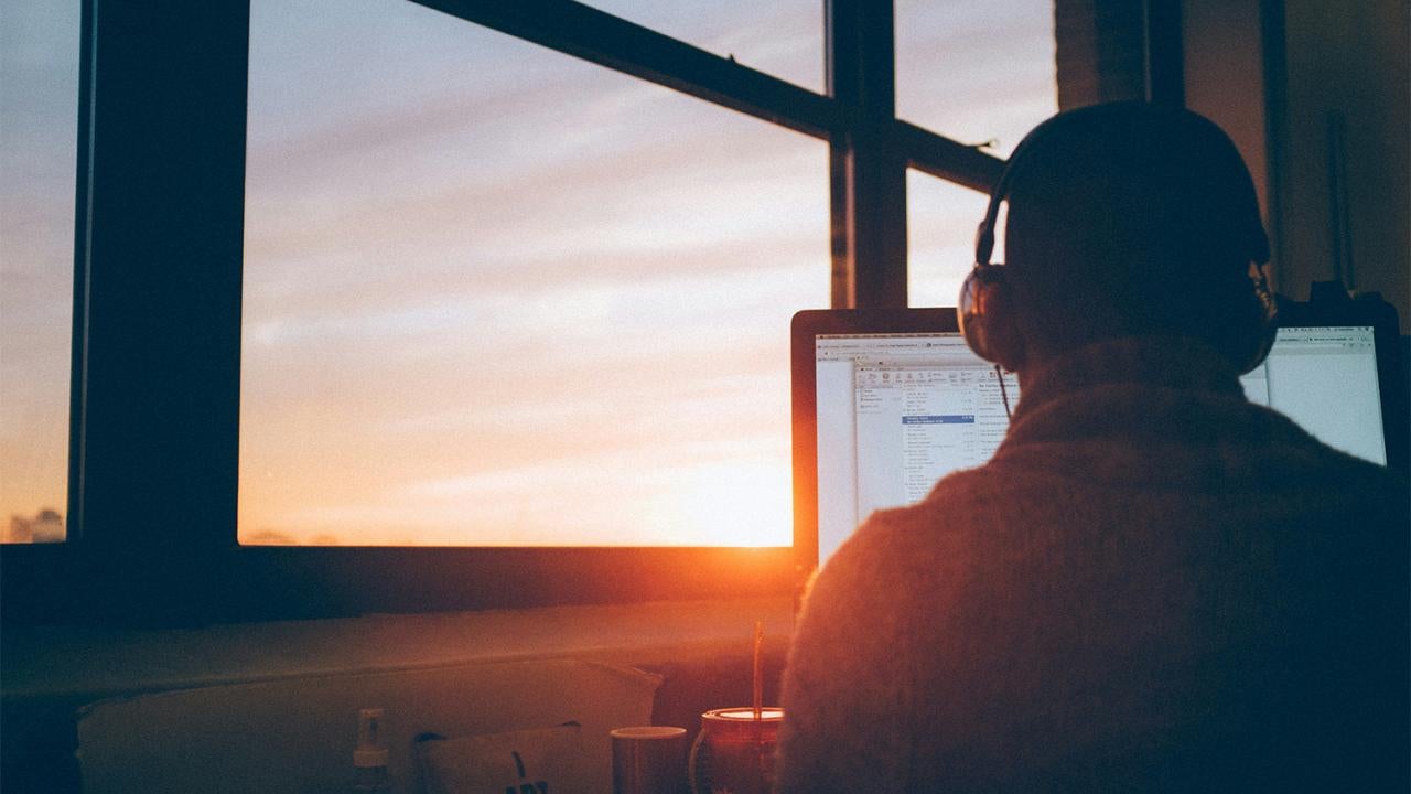 A person using a computer during sunset.